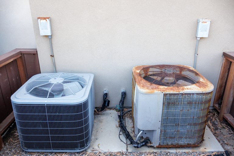 Residential HVAC setup showcasing a brand new grey air conditioner alongside a worn out old unit in enclosed outdoor pad